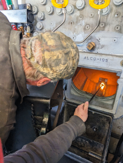 Man lighting fire in steam locomotive firebox.