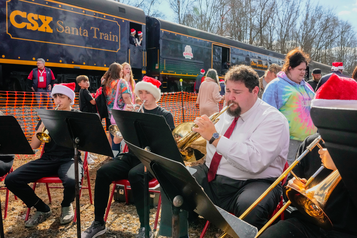 Seated musicians playing with train in background