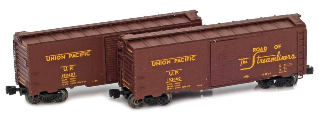 Color photo showing two Z scale 40-foot boxcars painted brown with yellow graphics on white background.