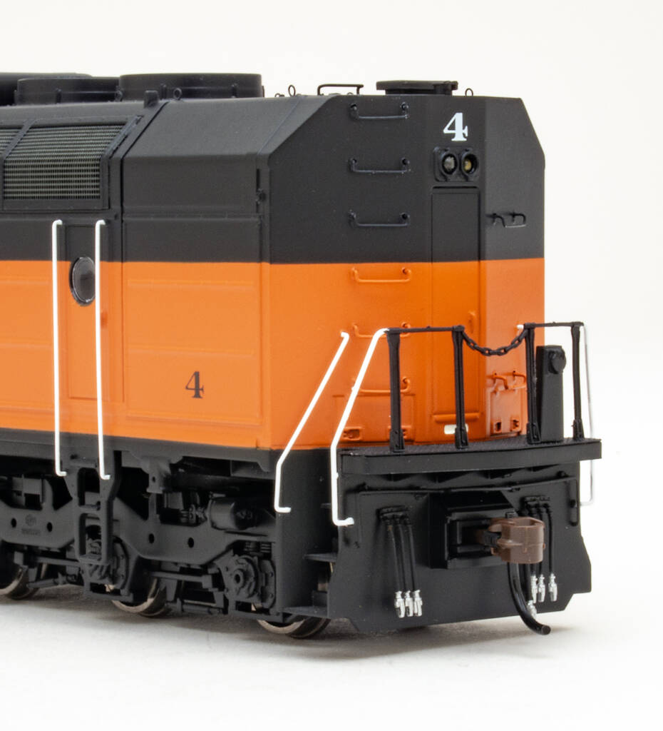 Color photo showing back and fireman’s side of HO scale six-axle cowl-body diesel painted orange and black on white background.