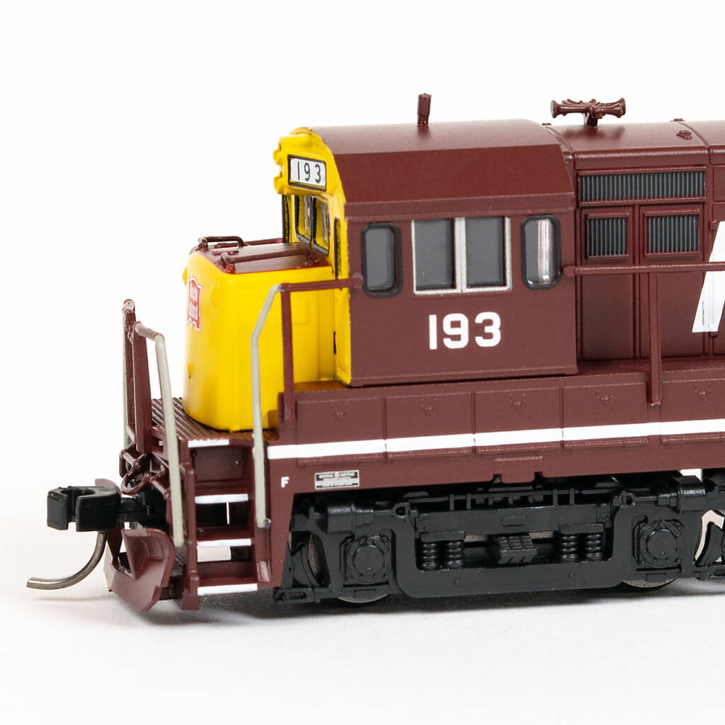 Color photo of four-axle N scale diesel locomotive painted maroon and yellow with white graphics on white background.