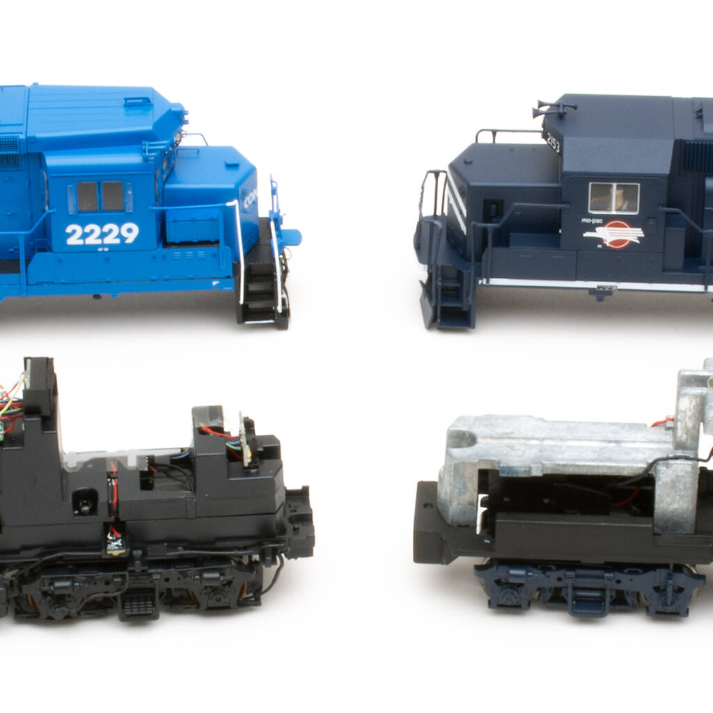 Color photo showing two HO scale locomotive shells, one dark blue and one light blue, with mechanisms in foreground on white background.