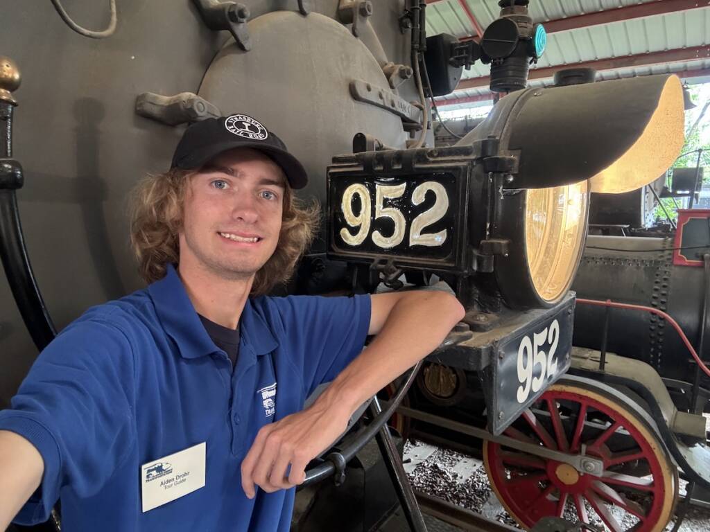 Young individual in front of a displayed steam locomotive