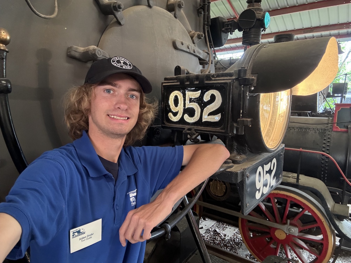 One of the young guns in preservation, Aiden Drohr, stands in front of a displayed steam locomotive