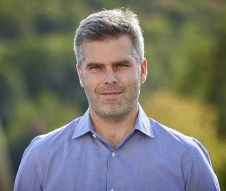 head shot of man in blue shirt in outdoor setting