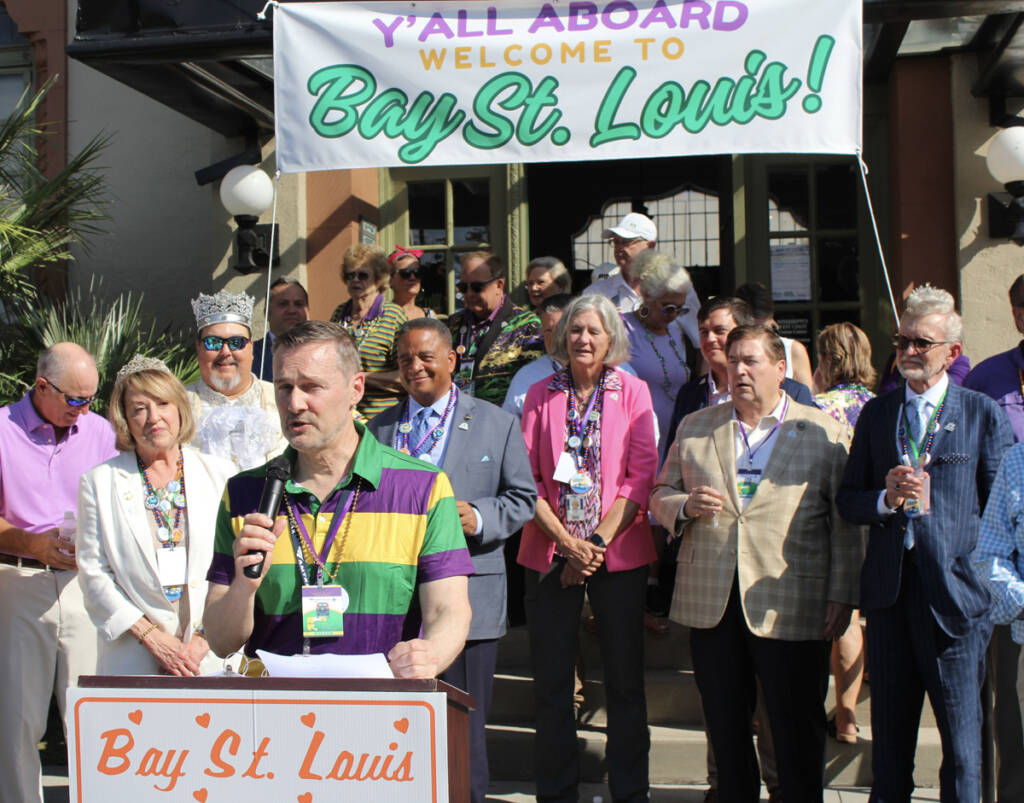 Man speaks at podium with large crowd of onlookers behind him