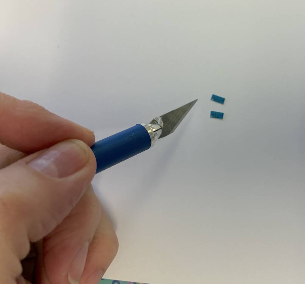 hobby knife next to tiny license plate pieces