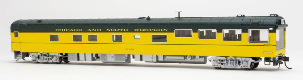 Color photo of lightweight passenger car painted green and yellow with silver trucks and underbody on white background.