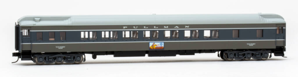 Color photo of N scale heavyweight sleeper painted two-tone gray with light gray roof and multi-color sign below windows on white background. 