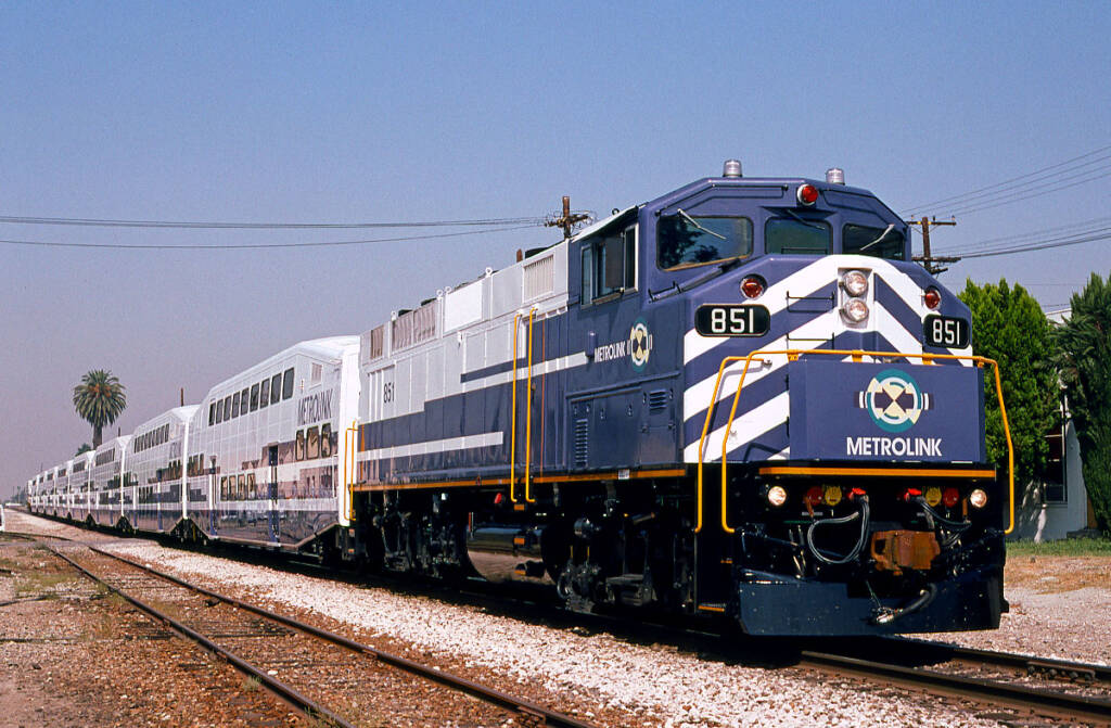 Blue and white diesel locomotive pulling bi-level commuter cars.