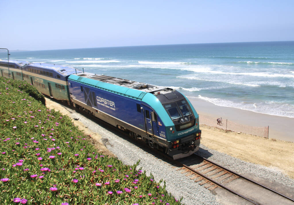 View from above of commuter train with Pacific Ocean in background.