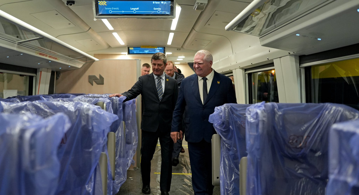 Men walking through passenger car with seats wrapped in plastic.