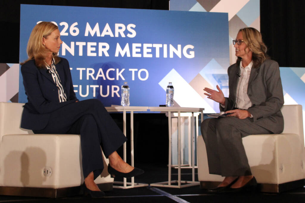 Two seated women facing each other in on-stage talk