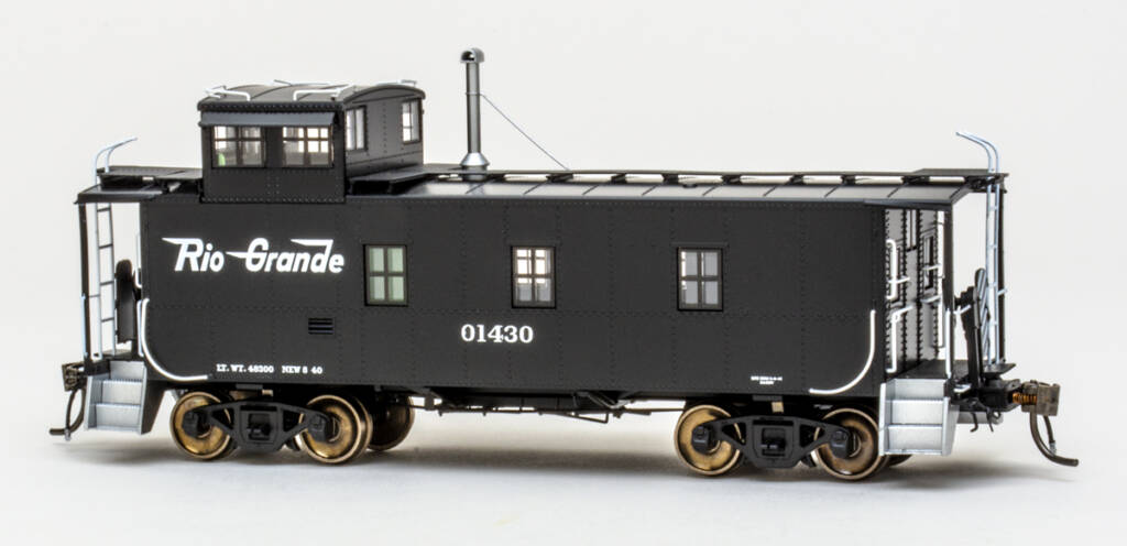 Color photo of HO scale caboose painted black with white graphics and silver end steps on white background. 