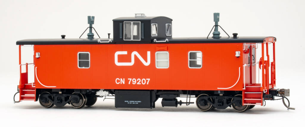 Color photo of HO scale caboose painted red and black with white graphics on white background.
