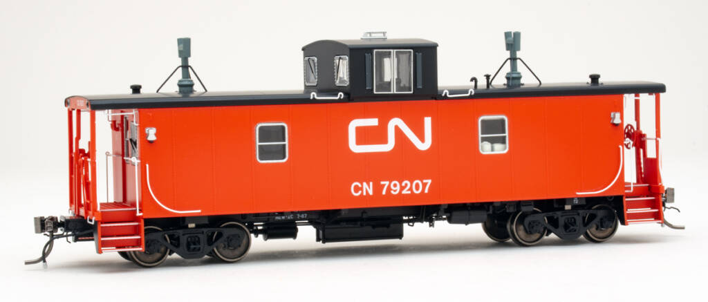 Color photo of HO scale caboose painted red and black with white graphics on white background.