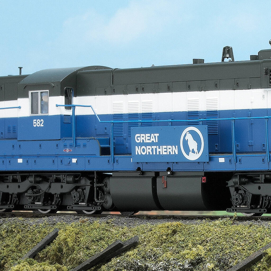 Color photo showing portion of EMD hood unit painted blue, white, and gray on scenicked base with a sky blue backdrop.
