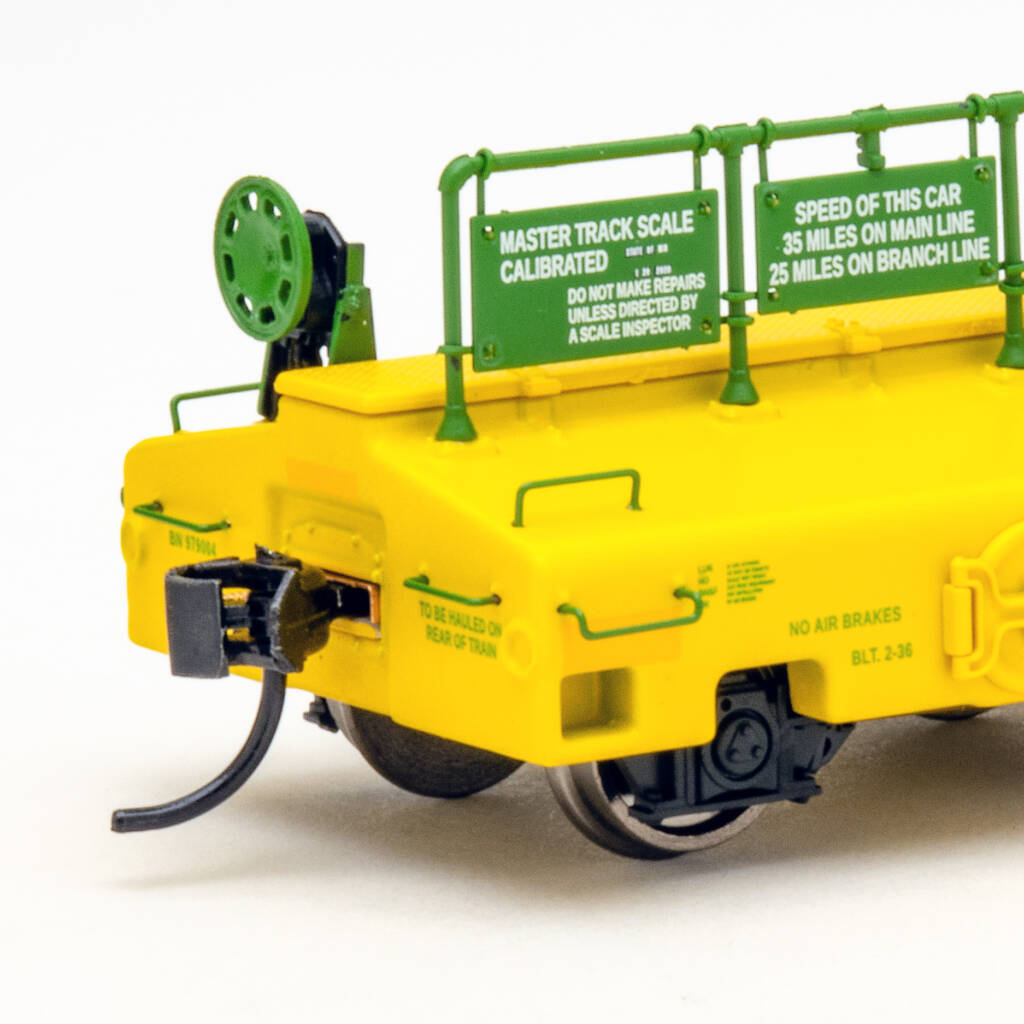 Color photo of scale test car painted yellow and green on white background.