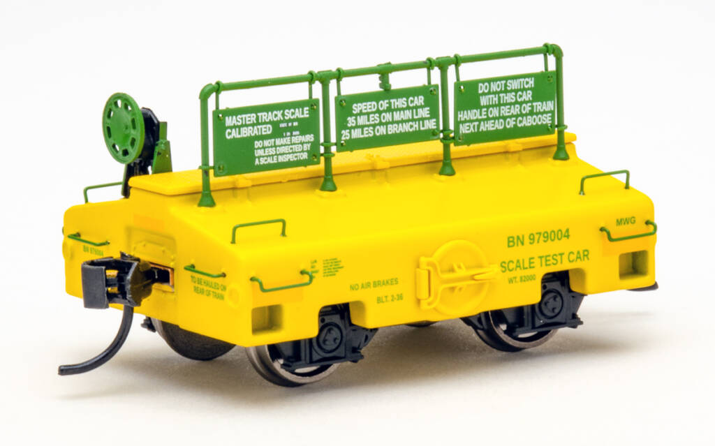 Color photo of scale test car painted yellow and green on white background.