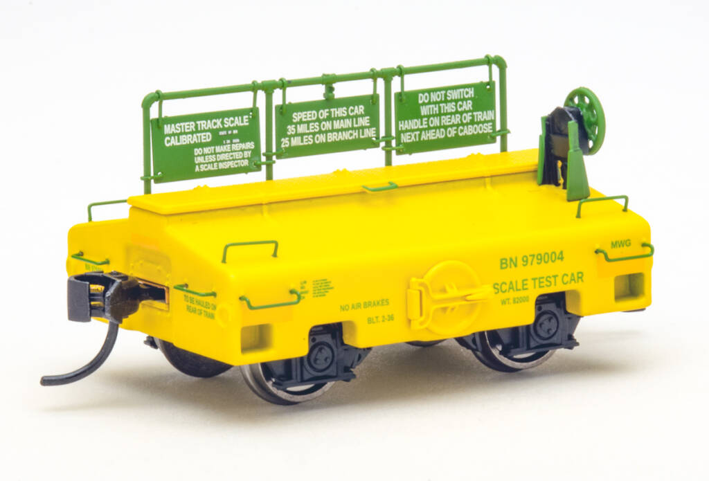 Color photo of scale test car painted yellow and green on white background.