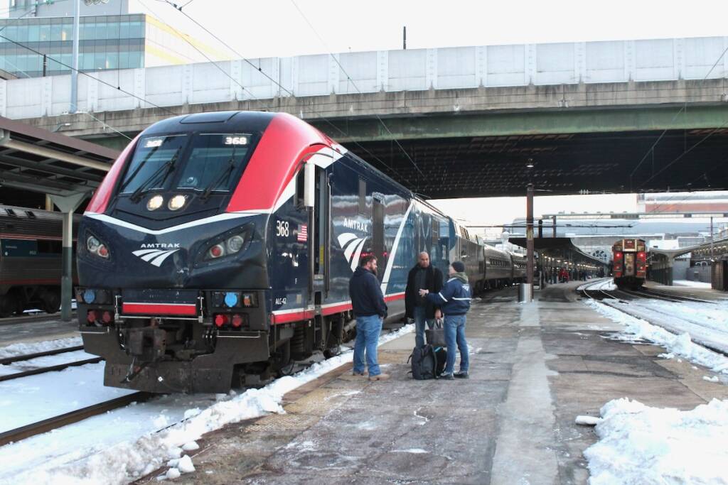 Crew members talking next to locomotive on station platform