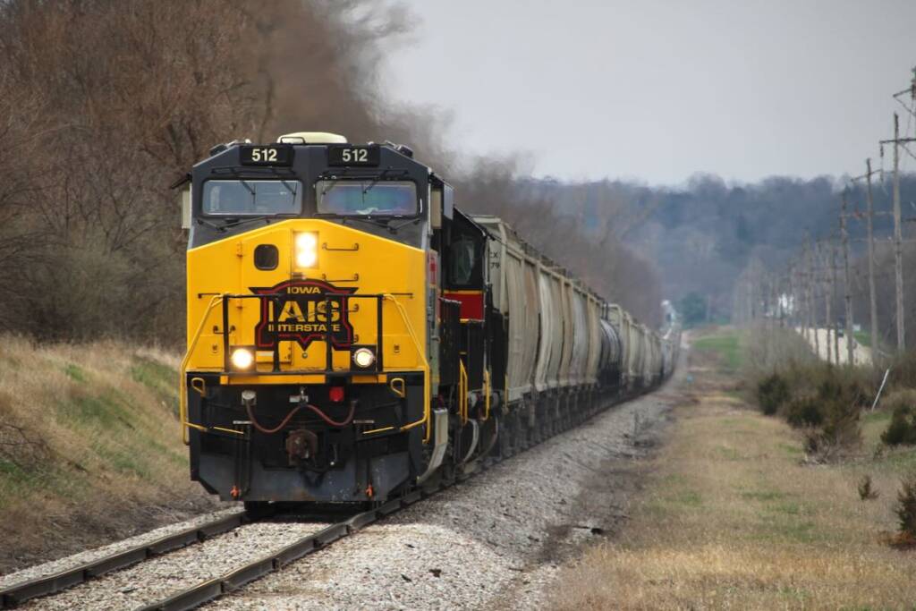Train with black, red and yellow locomotives on long grade.