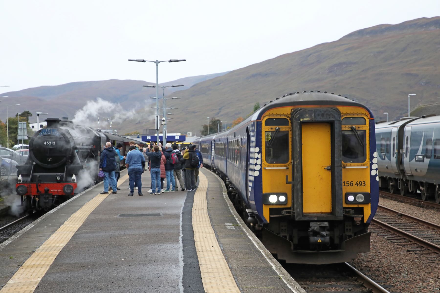 DMU train and steam tourist train on opposite sides of train platform.