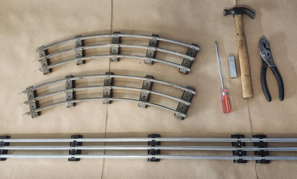three pieces of track and some tools on brown kraft paper