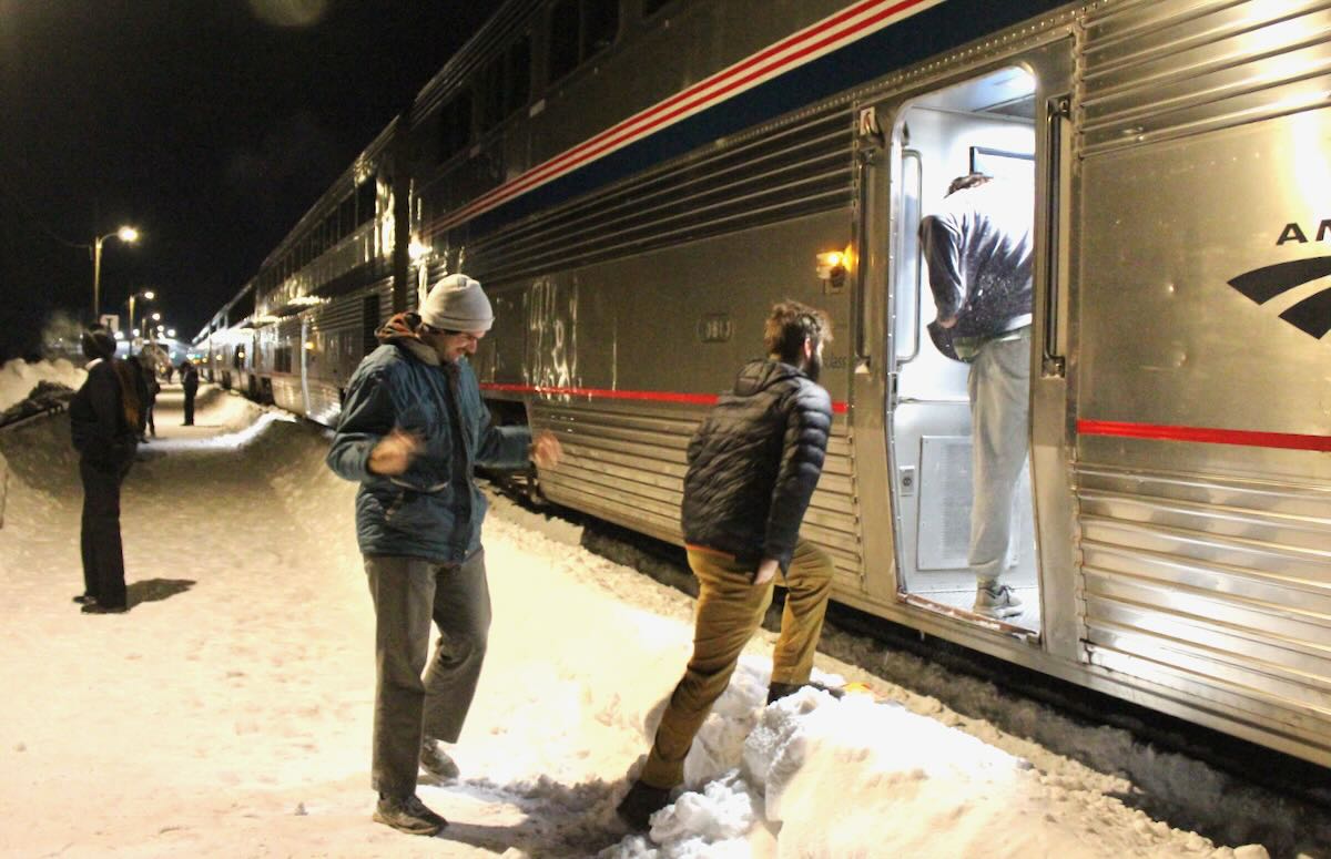 People boarding passenger train at night from snow-covered platform