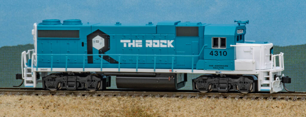 Color photo of N scale EMD hood unit painted blue and white with black and white graphics on scenicked base with a sky blue background.