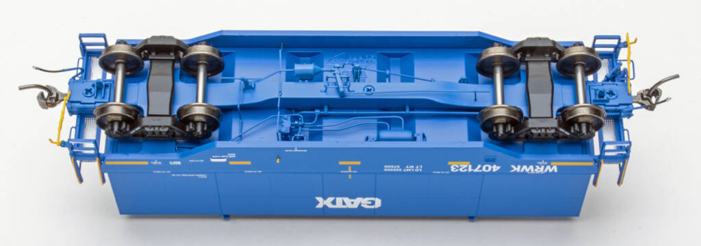 Color photo showing underbody of modern HO scale coil gondola with hood painted blue with white and yellow graphics and black trucks on white background.