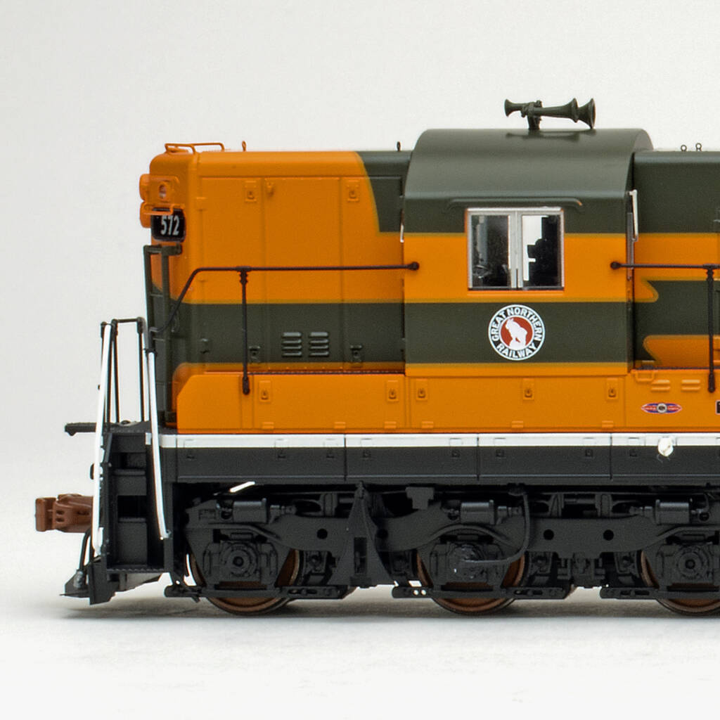 Color photo showing short hood and engineer's side of cab on an EMD six-axle hood unit painted orange, green, and yellow with black trucks, sill, and pilot on white background.