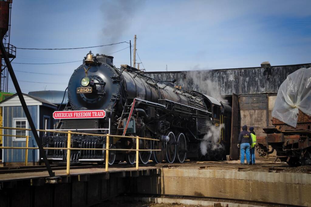 Locomotive under steam outside of roundhouse