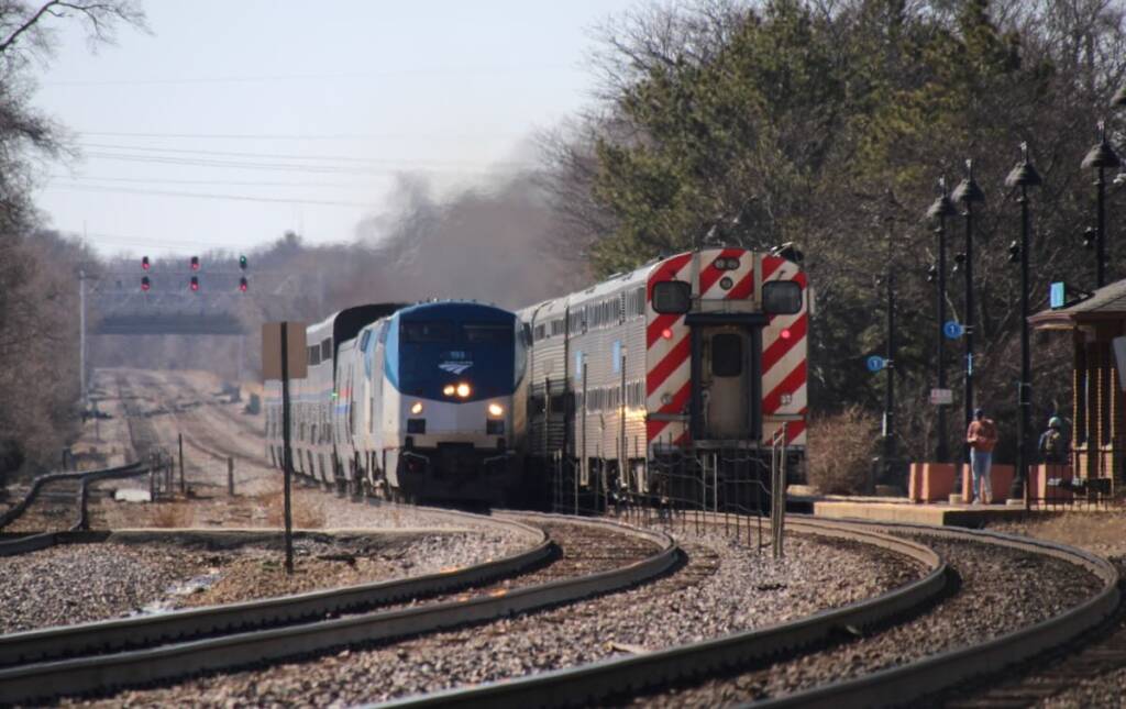 An Amtrak train runs alongside a Metra train on parallel tracks