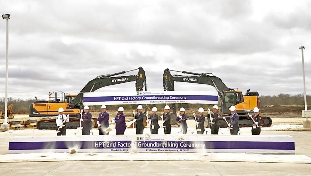 People in hard hats throwing shovels of dirt during groundbreaking ceremony